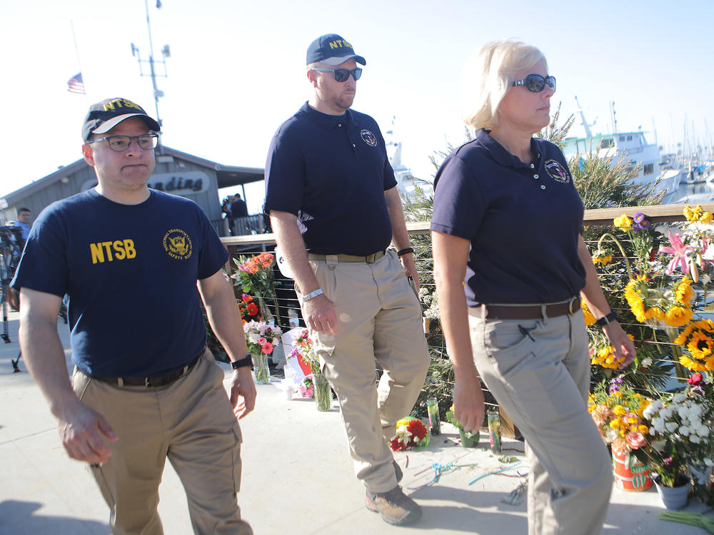 National Transportation Safety Board member Jennifer Homendy (right) walks with other NTSB officials past a makeshift memorial for victims of the Conception boat fire in September 2019 in Santa Barbara, Calif.