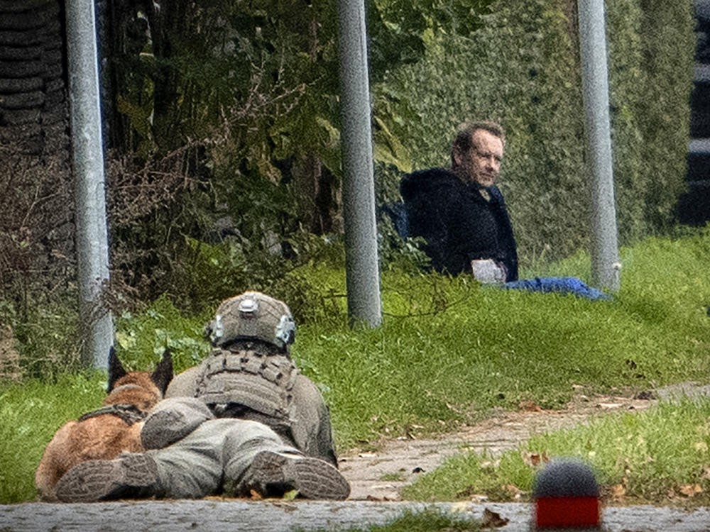 A police marksman and his dog observes convicted killer Peter Madsen threatening police with detonating a bomb while attempting to break out of jail Tuesday in Albertslund, Denmark.