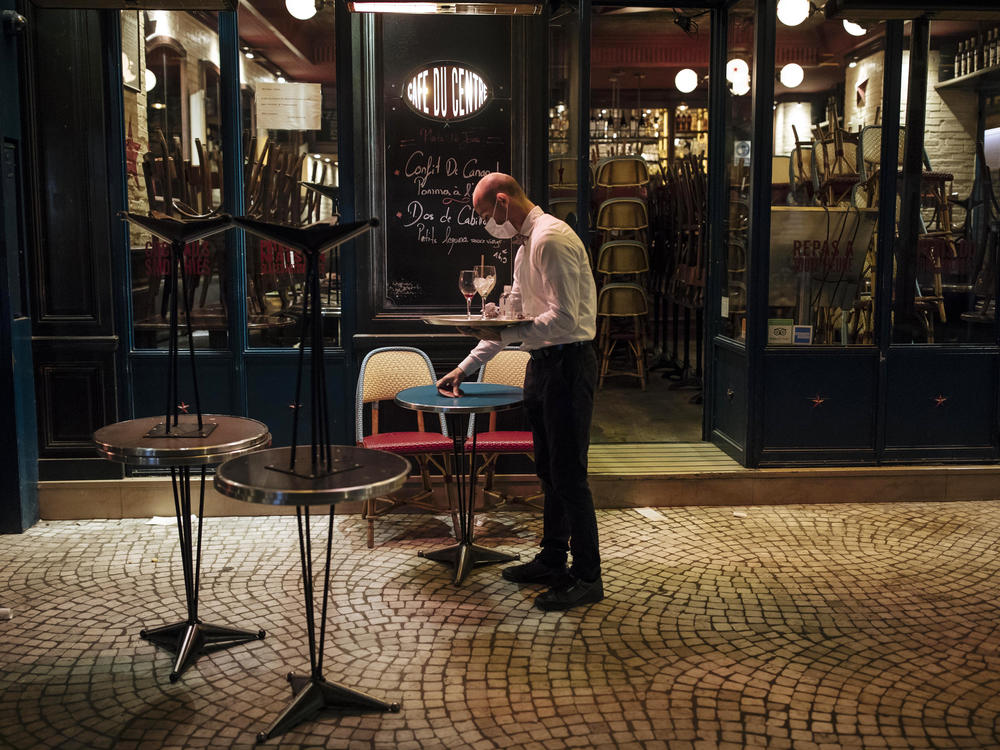 A waiter closes a bar terrace in Paris earlier this month amid a surge in coronavirus cases.