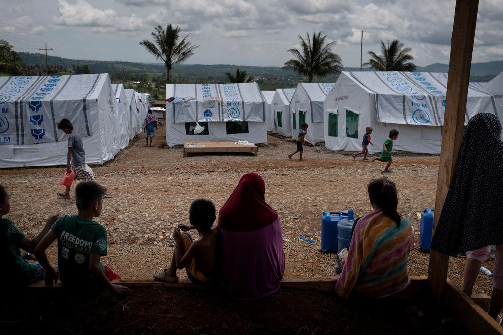 Displaced Marawi residents huddle under shade inside a makeshift tent shelter area in 2018.