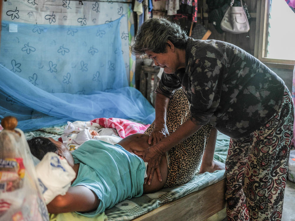 Florida Domingo massages Calibuso's belly. The early morning massage is part of a traditional healing process after delivery.