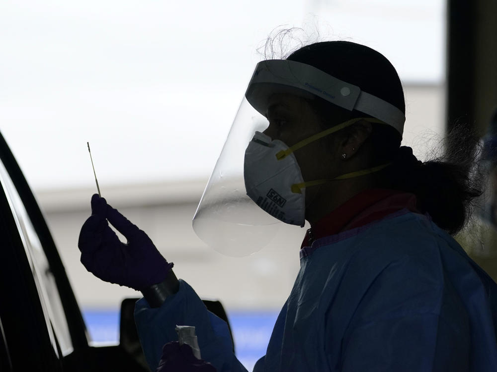 A University of Washington research coordinator holds up a swab after testing a someone for coronavirus on Oct. 23 in Seattle. The U.S. recorded a record high number of new daily cases Friday.