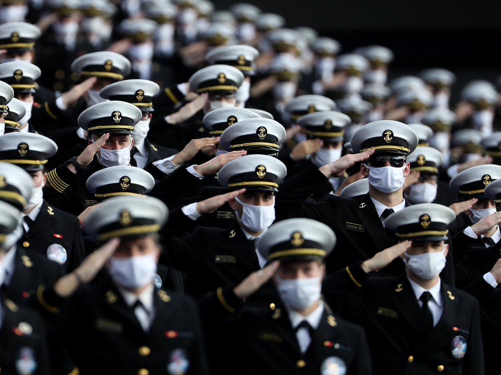 Midshipmen wearing face masks stand and salute before the Navy Midshipmen play against the Houston Cougars on Saturday in Annapolis, Md. Researchers have tried to estimate how many lives would be saved by universal mask-wearing.