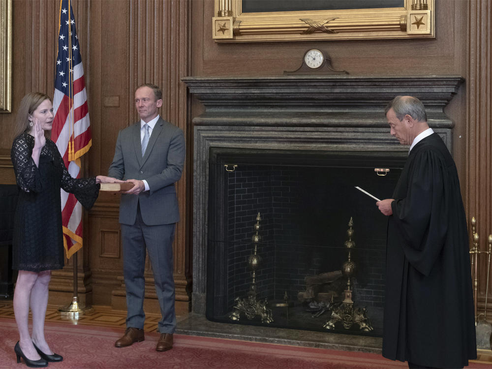 Chief Justice John Roberts Jr. administers the judicial oath to Judge Amy Coney Barrett at the Supreme Court on Tuesday. Barrett's husband, Jesse, holds the Bible.