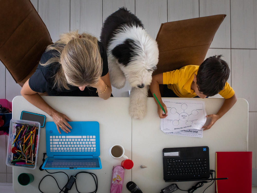 A mother works from home while her son attends school remotely in an arranged photograph taken in Miami in September.