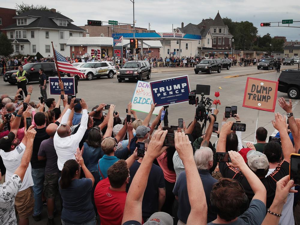Trump supporters and Trump protesters watch a passing motorcade carrying the president last month in Kenosha, Wis.
