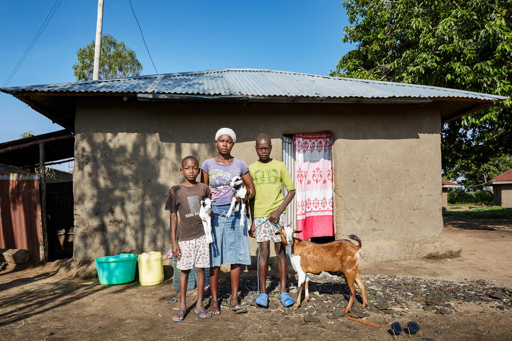 Cheryl Awuor stands by her house with sons Rolines (left) and Brian (right) in November 2019. Awuor is part of a community banking group: Members give money each week into a collective pot, take out loans in times of need and are occasionaly given a bonus: a goat (hers is pictured above). She hoped raising goats would help sustain her family but the flooding carried her livestock away.