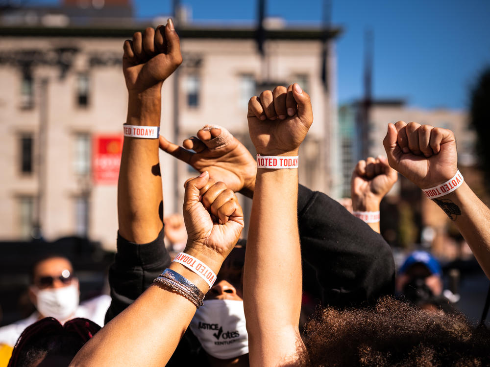 Black Lives Matter protesters display wristbands reading 