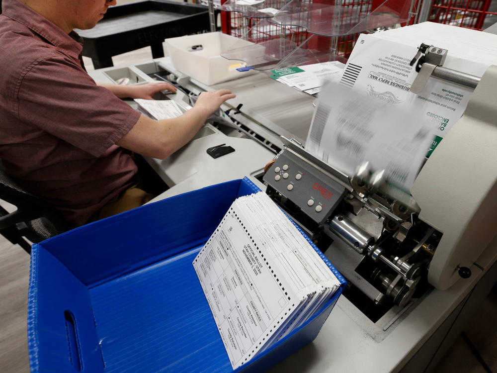 An election worker opens envelopes and removes ballots so they can be counted at the election office on Octo. 26, 2020 in Provo, Utah.