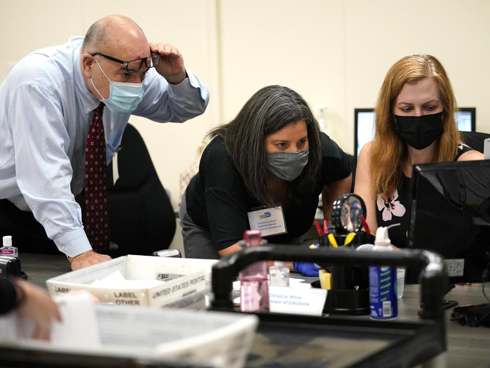 Miami-Dade County Supervisor of Elections Christina White (right) examines signatures on vote-by-mail ballots with members of the Canvassing Board.