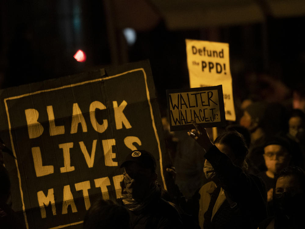 Demonstrators hold placards reading 