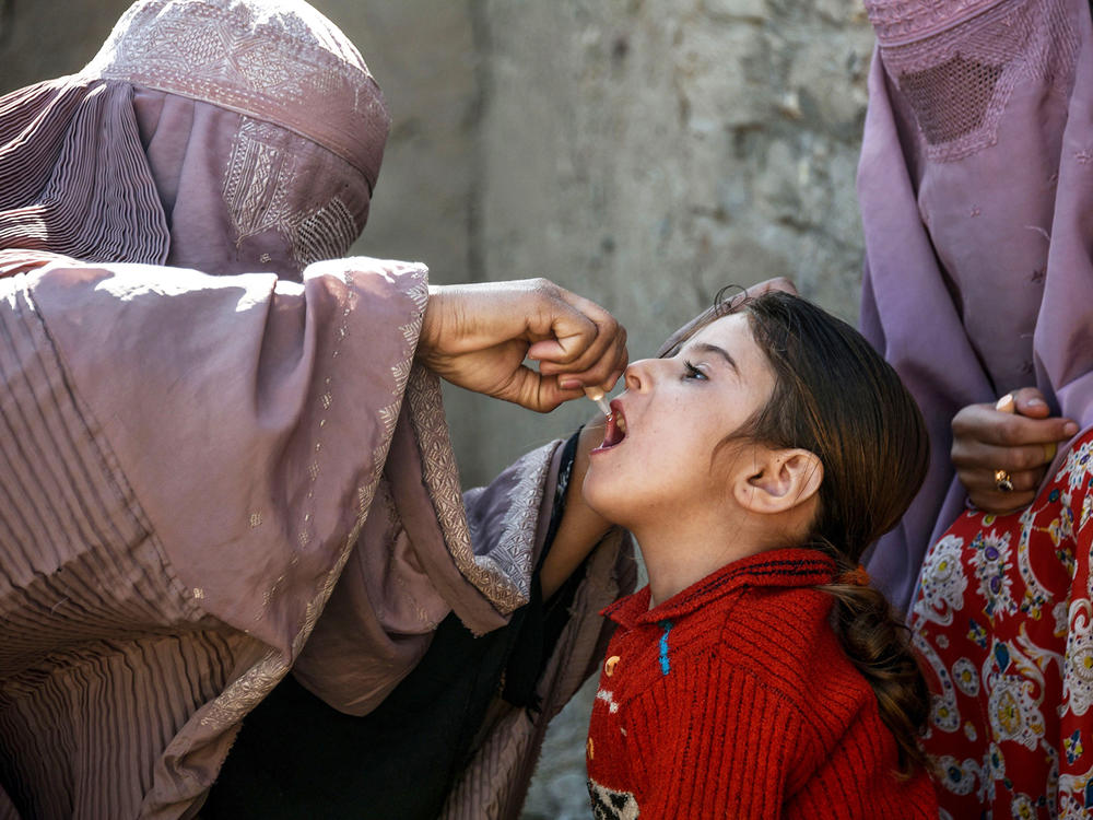 A health worker administers a polio vaccine to a child in Afghanistan's Kandahar province. Taliban opposition to vaccine campaigns have left millions of children unprotected against the virus.