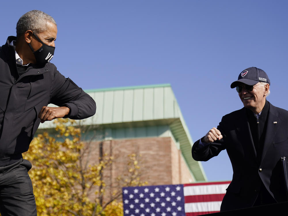 Democratic presidential nominee Joe Biden and former President Barack Obama greet each other at a drive-in rally in Flint, Mich.