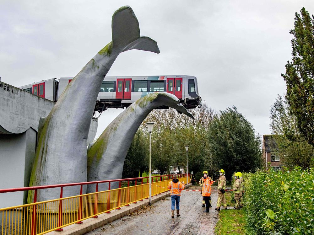 A massive sculpture of a whale's tail keeps a metro train aloft Monday after it shot through a stop block at De Akkers station in Spijkenisse, Netherlands. No injuries were reported.