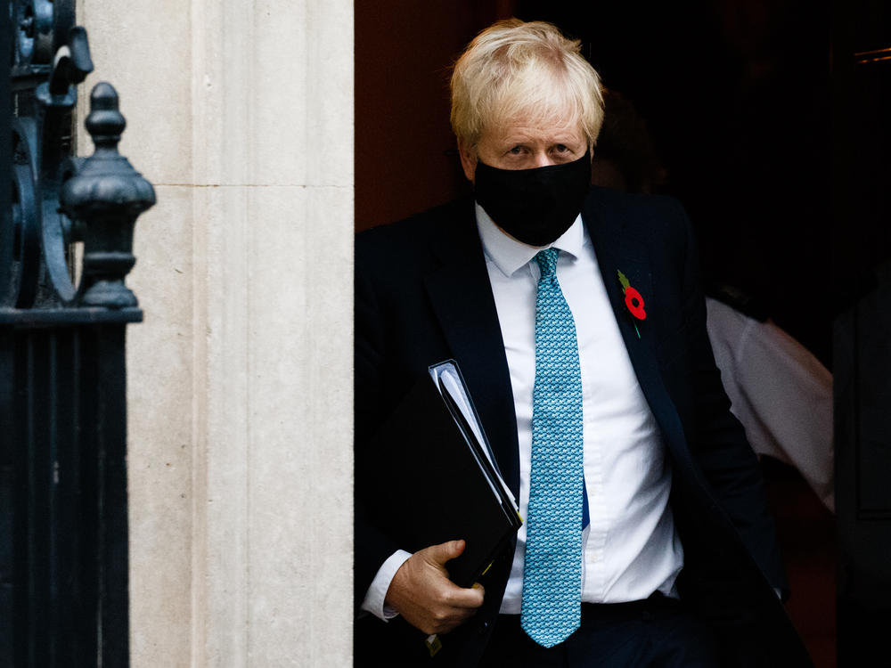 British Prime Minister Boris Johnson wears a mask and remembrance poppy as he leaves No. 10 Downing St. heading for the Houses of Parliament in London after ordering a new England-wide coronavirus lockdown.
