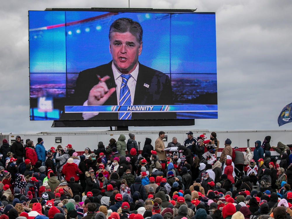 Supporters of President Trump watch a video featuring Fox News host Sean Hannity ahead of Trump's arrival for a campaign rally Friday in Waterford Township, Mich.