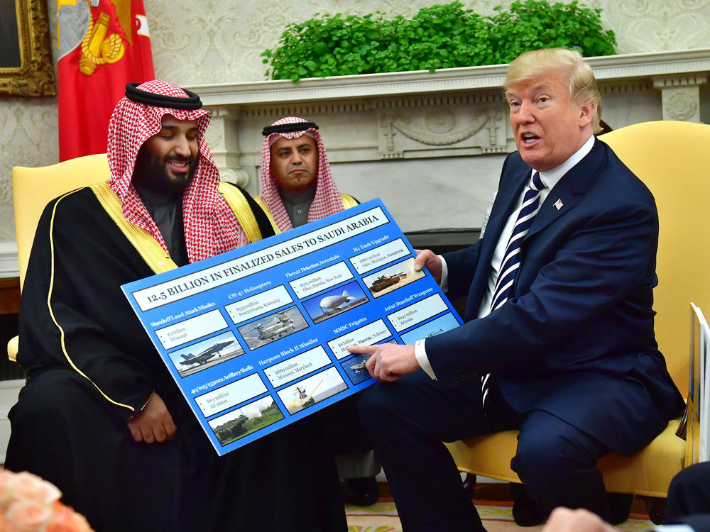 Saudi Crown Prince Mohammed bin Salman (left) meets with Trump, who holds a chart displaying military hardware sales, in the Oval Office of the White House in March 2018.