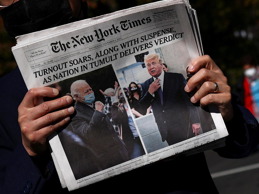 A man holds a fresh copy of <em>The New York Times</em> on Wednesday morning on Black Lives Matter Plaza near the White House.