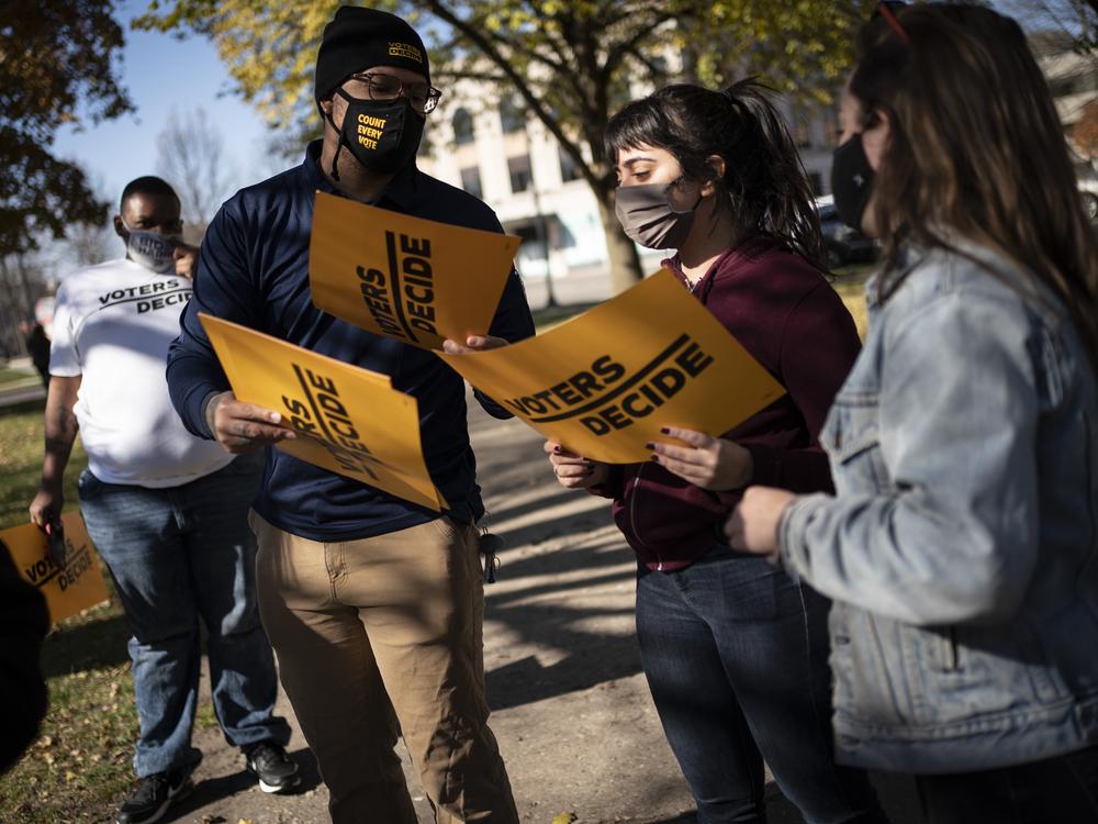 People gather with signs that read 