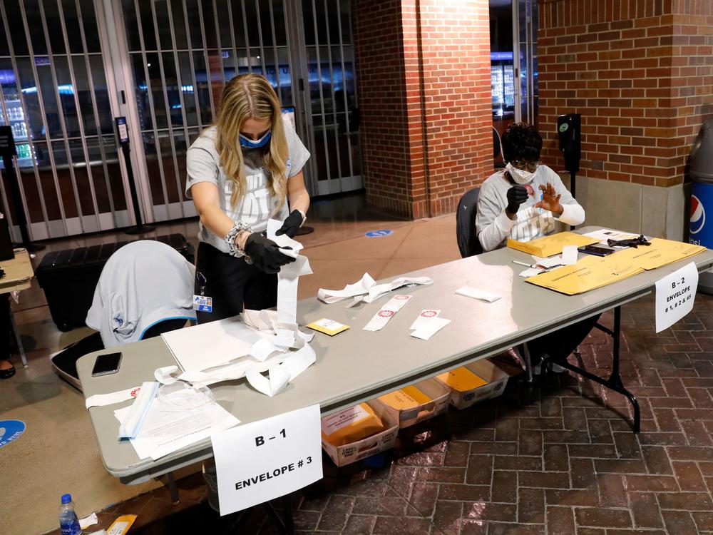 Election workers check the tapes from the voting machines to verify they contain the correct signatures from polling stations after polls closed in the general election at Ford Field on November 3, 2020 in Detroit.