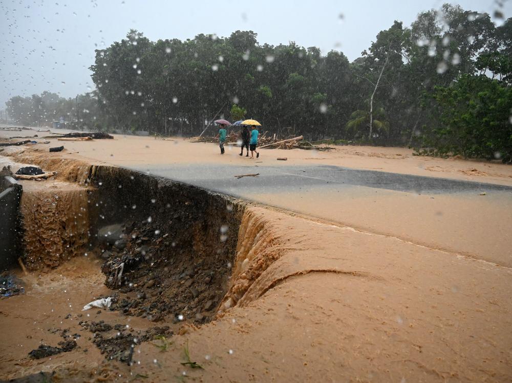 Men walk along a flooded road Wednesday in Toyos, Honduras, after heavy rains from Eta caused a river to overflow.