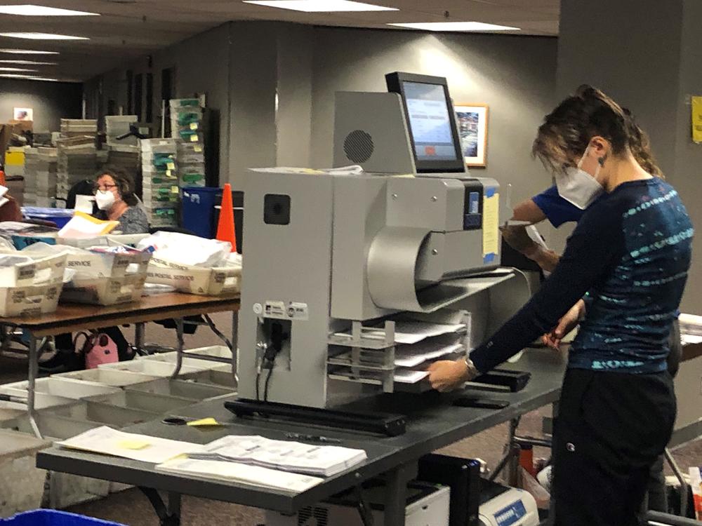 Election workers in Milwaukee are seen feeding absentee ballots into tabulating machines late Tuesday night. The state's 10 electoral votes were awarded to Democrat Joe Biden. But the Trump campaign signaled they will call for a recount.