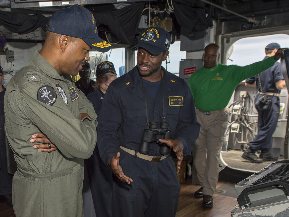 Rear Adm. Alvin Holsey (left) speaks with Ensign Dimitri Foster in the pilothouse aboard guided-missile cruiser USS Lake Champlain in 2018.
