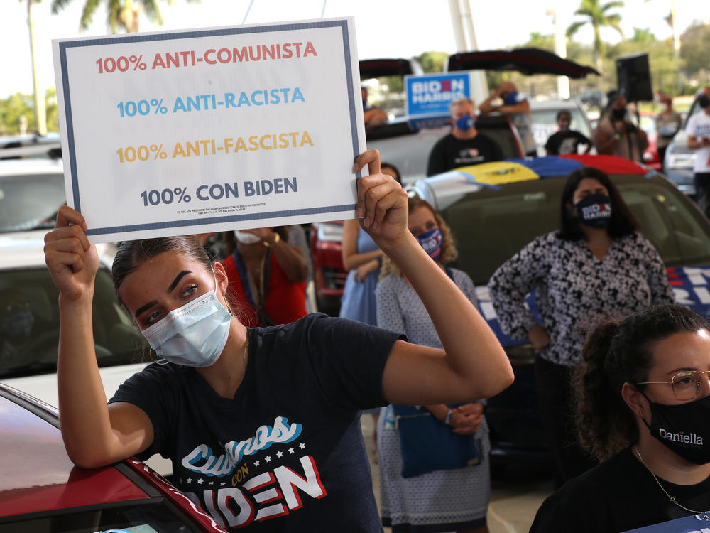 Wearing a face masks to reduce the risk posed by the coronavirus, Sophia Hildalgo (L) and Amore Rodriguez of Miami stay with their car decorated in Cubans for Biden paint.