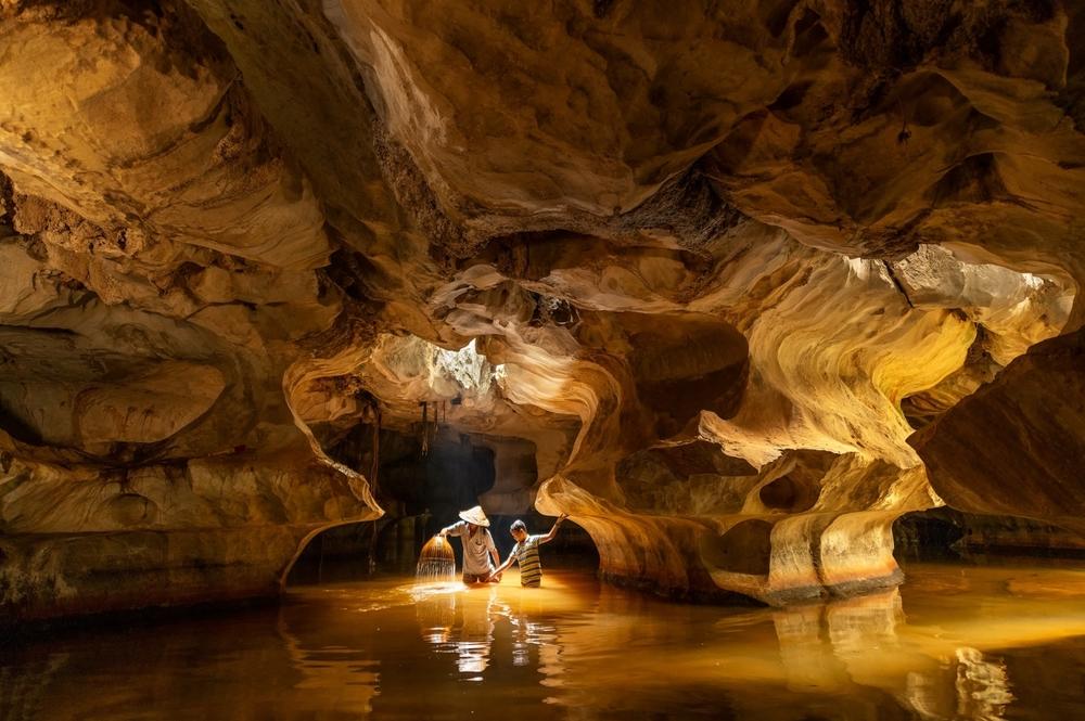 A father and son catch fish inside a cave in Vietnam during the monsoon season.
