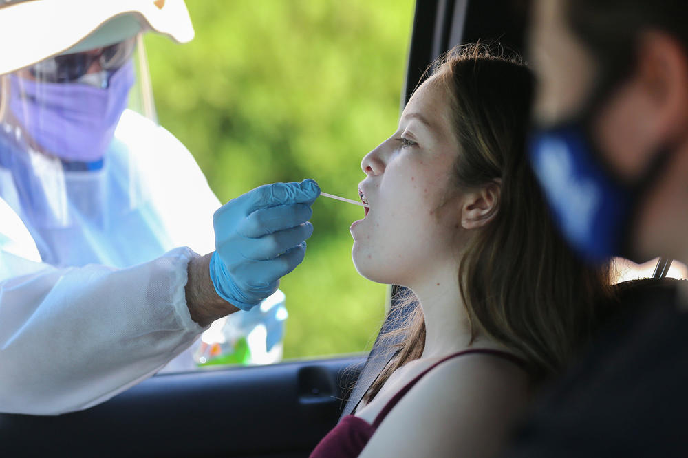 A health care worker administers a throat swab test at a drive-in COVID-19 testing center.