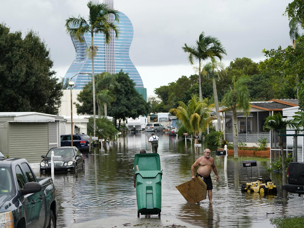 Residents clear debris from a flooded street in the Driftwood Acres Mobile Home Park, in the aftermath of Tropical Storm Eta, on Tuesday in Davie, Fla.