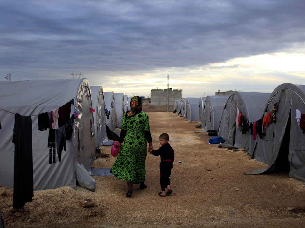 A Kurdish refugee mother and son from the Syrian town of Kobani walk beside their tent in a camp in the Turkish town of Suruc on the Turkish-Syrian border in 2014. President-elect Joe Biden aims to reverse the Trump administration's dramatic cuts to refugee admissions.