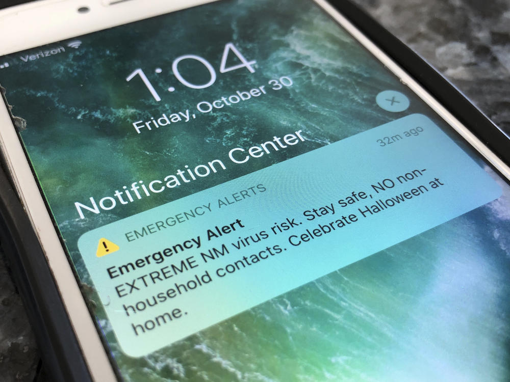 An emergency alert regarding the coronavirus pandemic is displayed on a cellphone Friday in Rio Rancho, N.M. The alert was sent out to New Mexicans across the state urging them to stay home amid a surge in COVID-19 cases and record-high hospitalizations.