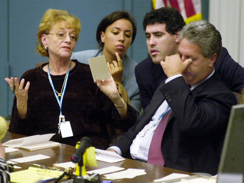 Palm Beach County canvassing board chairman Judge Charles Burton rubs his eyes as board member Carol Roberts (left) shows a questionable ballot to the Democratic attorneys during the hand counting of ballots in West Palm Beach, Fla., on Nov. 22, 2000.