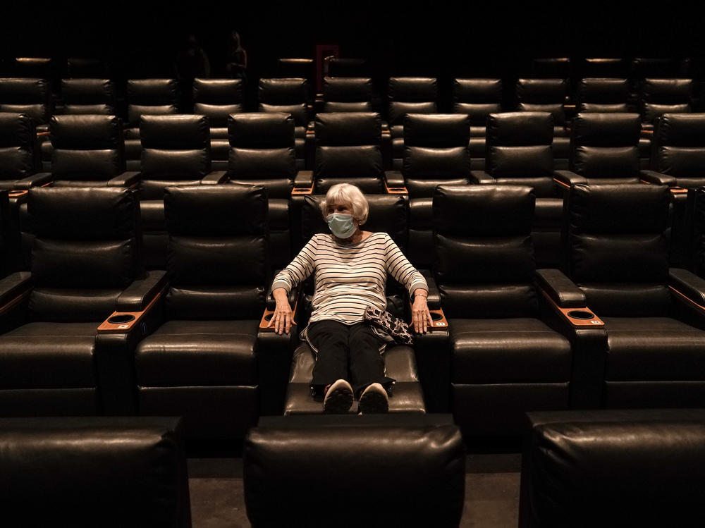 A woman sits in a theater in Irvine, Calif., waiting for a movie to start, on Sept. 8. A COVID-19 vaccine could unleash pent-up spending from households that have mostly avoided activities like going to the gym during the coronavirus pandemic.