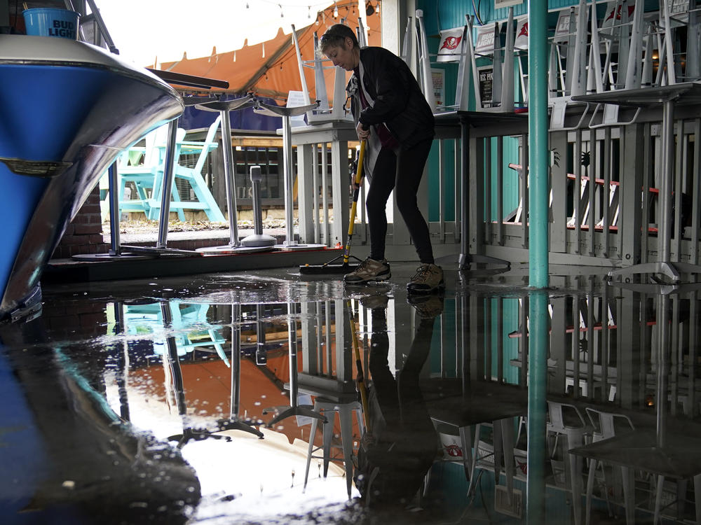 Kate Connell sweeps water and mud from the floor at Salty's Gulfport bar Thursday in Gulfport, Fla., in the aftermath of Tropical Storm Eta.