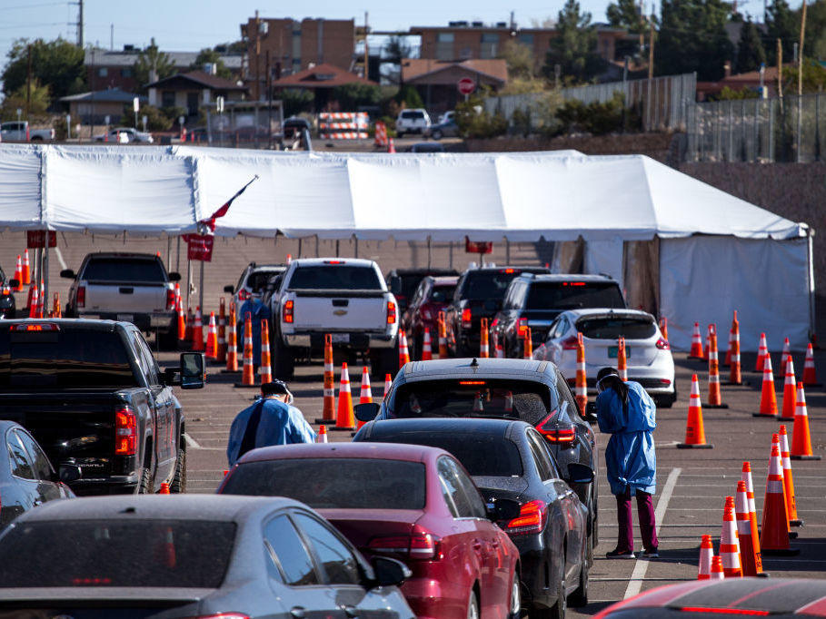 Medical workers wearing personal protective equipment register people in vehicles at a drive-through coronavirus testing site Monday in El Paso, Texas.