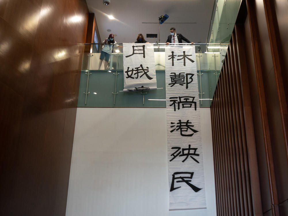 Pro-democracy lawmaker Lam Cheuk-ting hangs banners during a session at the Legislative Council outside of the main chamber on Thursday in Hong Kong. Fifteen pro-democracy lawmakers resigned en masse after four colleagues were disqualified from serving.