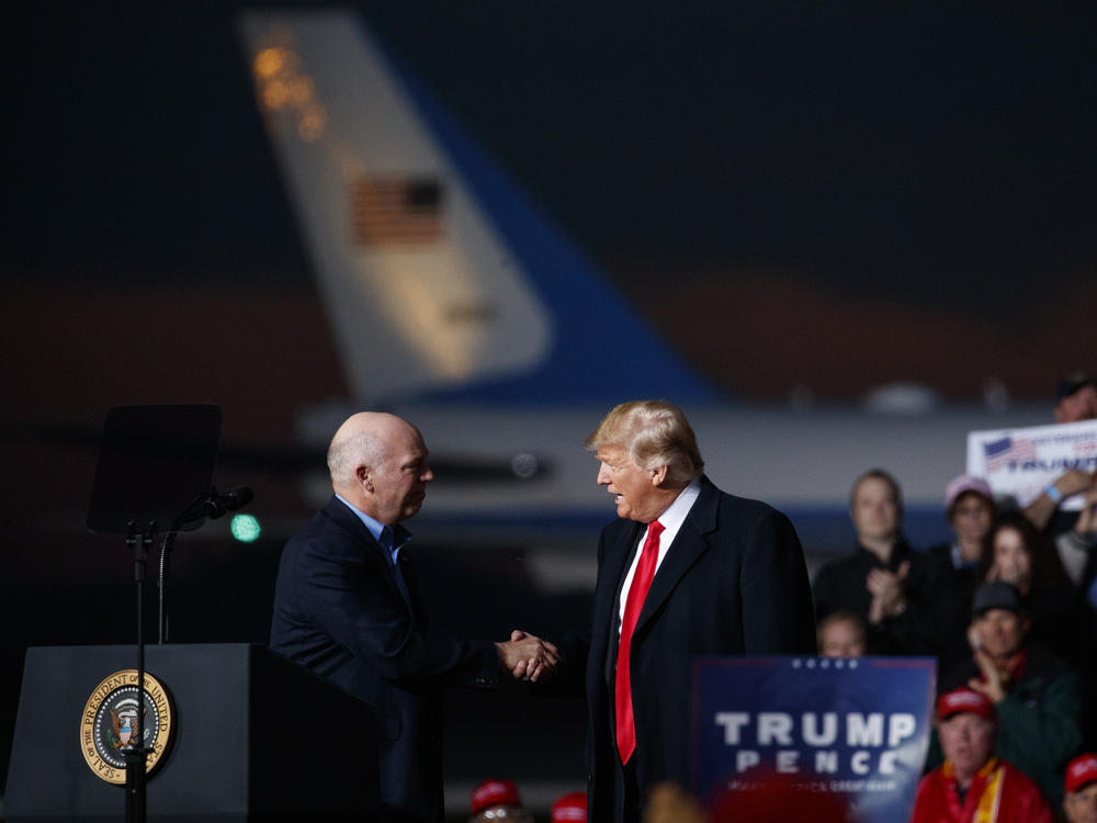 Greg Gianforte, now Montana's Republican governor-elect, and President Donald Trump shake hands on stage during a campaign rally on Oct. 18, 2018, in Missoula, Mont.
