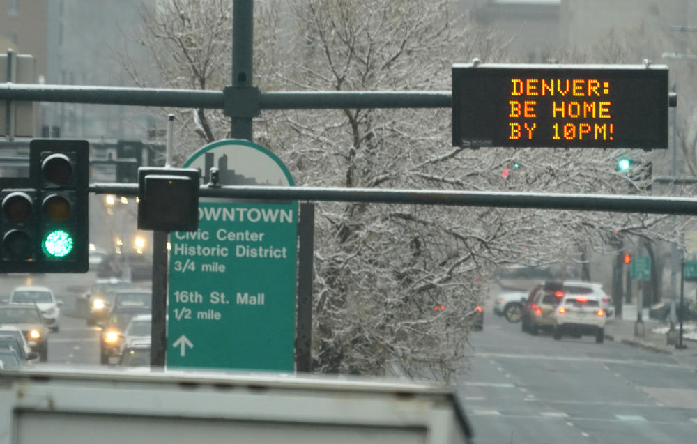 An electronic overhead sign in downtown Denver on Monday reminds residents to follow a curfew put into effect to curb the spread of the coronavirus.