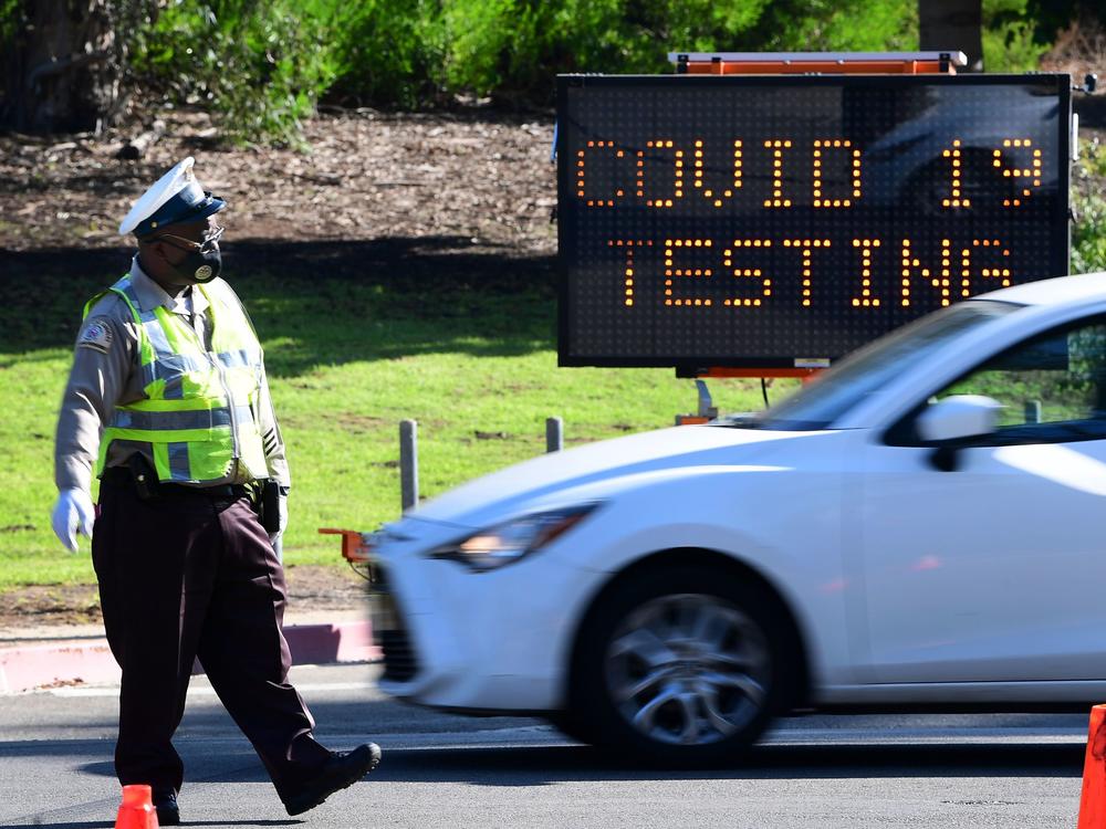 A traffic warden directs traffic as people arrive and depart from the coronavirus testing venue at Dodger Stadium in Los Angeles on Thursday.