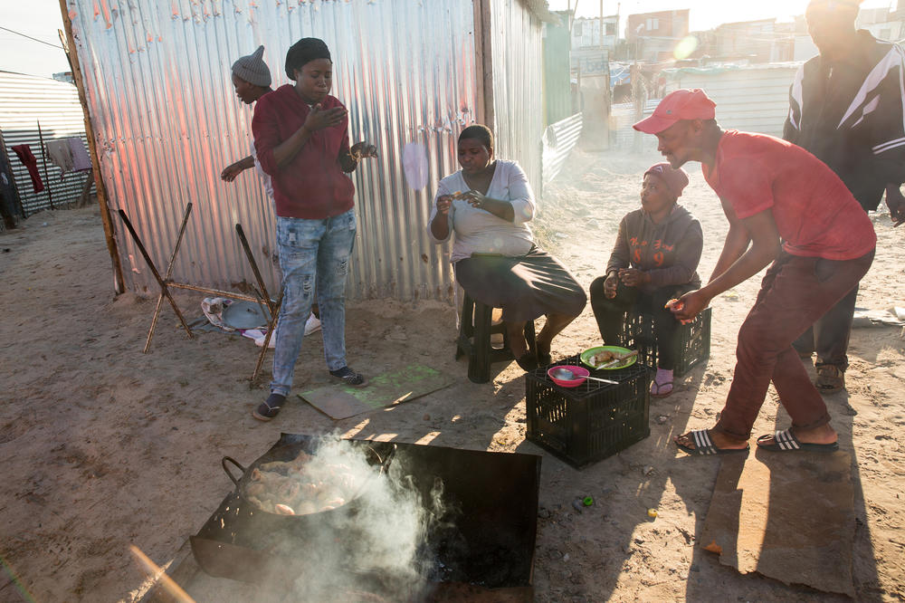 Many residents don't having proper cooking facilities in their shacks (or money to buy items in bulk). So street food is common. Linda Maseko (left, wearing jeans) has a bite with other residents.