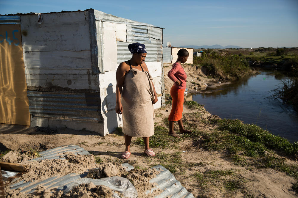 Nomthandazo Tyikiane (in the towel) and Siphamandala Tebekwana survey the damage done by the Kuils River the night before during a storm. Tyikiane's shack was destroyed so she was sleeping at a friends. 