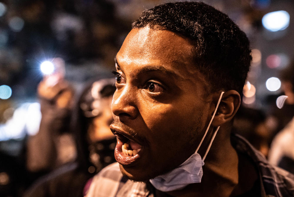 A counterprotester asks police officers who formed a line between counterprotesters and Trump supporters, 