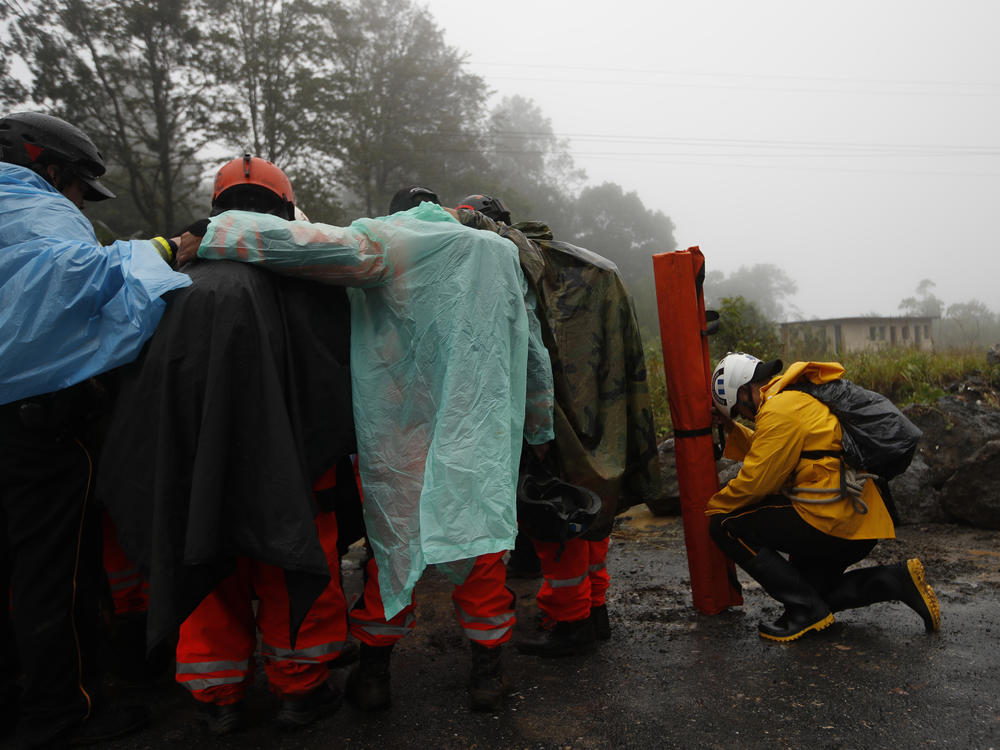 Volunteer firefighters huddle in prayer before beginning a search and rescue operation Nov. 7 in San Cristóbal Verapaz, Guatemala, in the aftermath of Hurricane Eta.