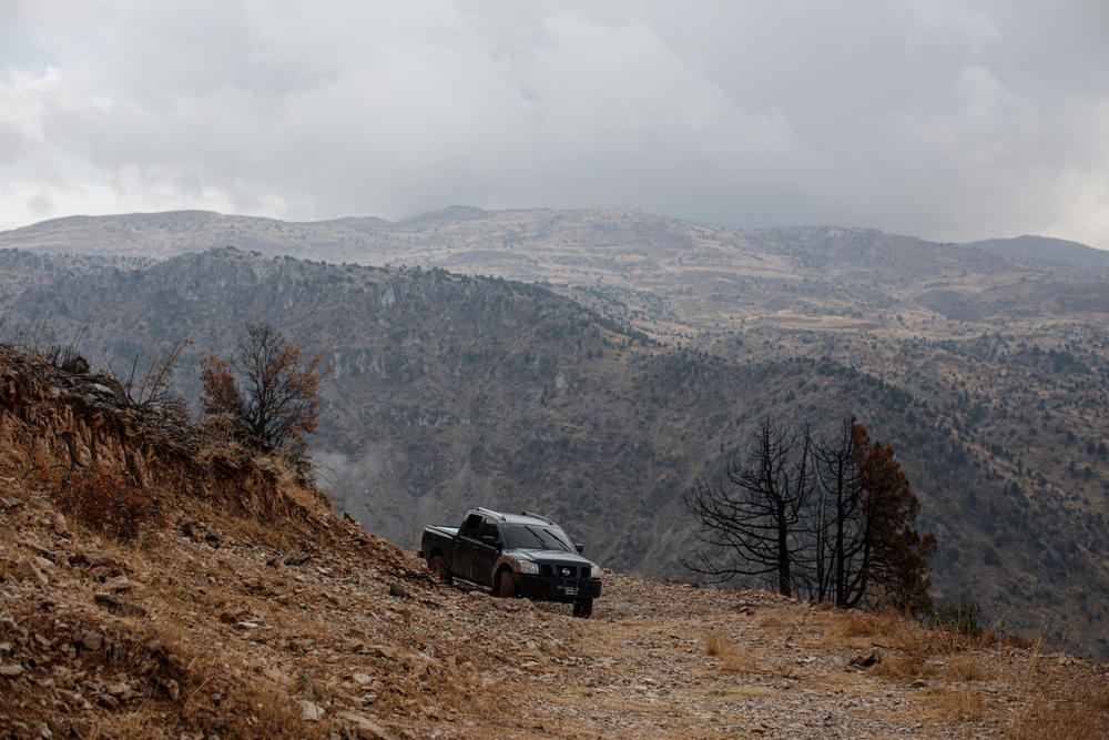 A pick-up truck that's been modified to be used for fighting wildfires is parked amid cedar and juniper trees that were burned in a recent wildfire, in the Mishmish forest.