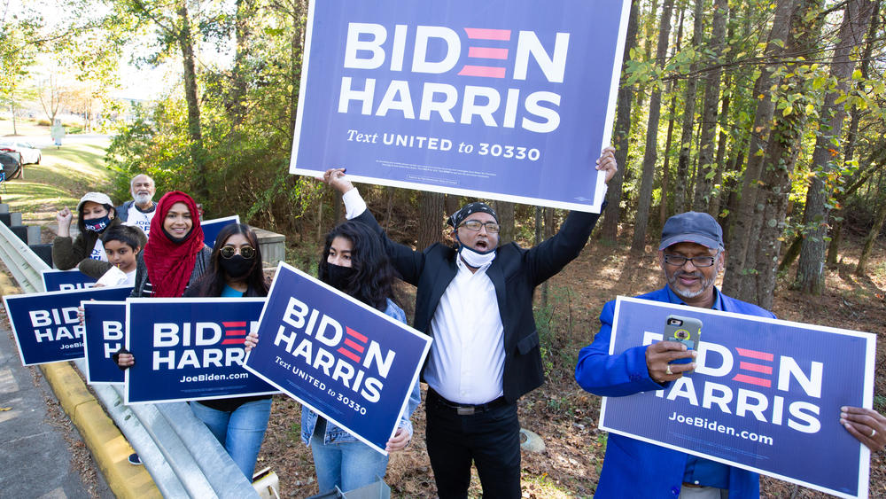 Residents of Gwinnett County in Georgia hold Biden-Harris campaign signs on Election Day in Norcross, Ga. President-elect Joe Biden ran up the margins in Atlanta's diversifying suburbs.