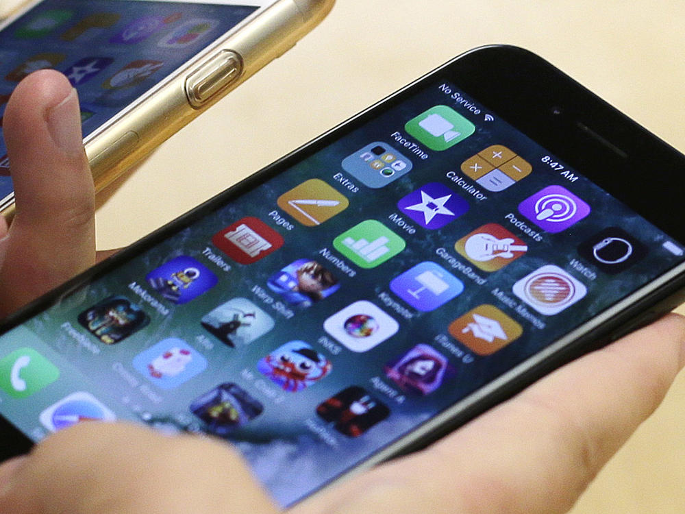 A customer compares her iPhone 6 (left) with an iPhone 7 at an Apple Store in Chicago. On Wednesday, more than 30 states announced a settlement with Apple over the company's past practice of slowing down a phone's battery.