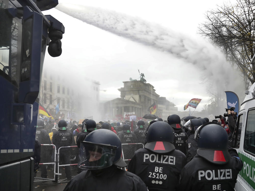 Police use water cannons to clear a road between the Brandenburg Gate and the Reichstag, home of the German parliament, as people attend a protest rally Wednesday in Berlin.