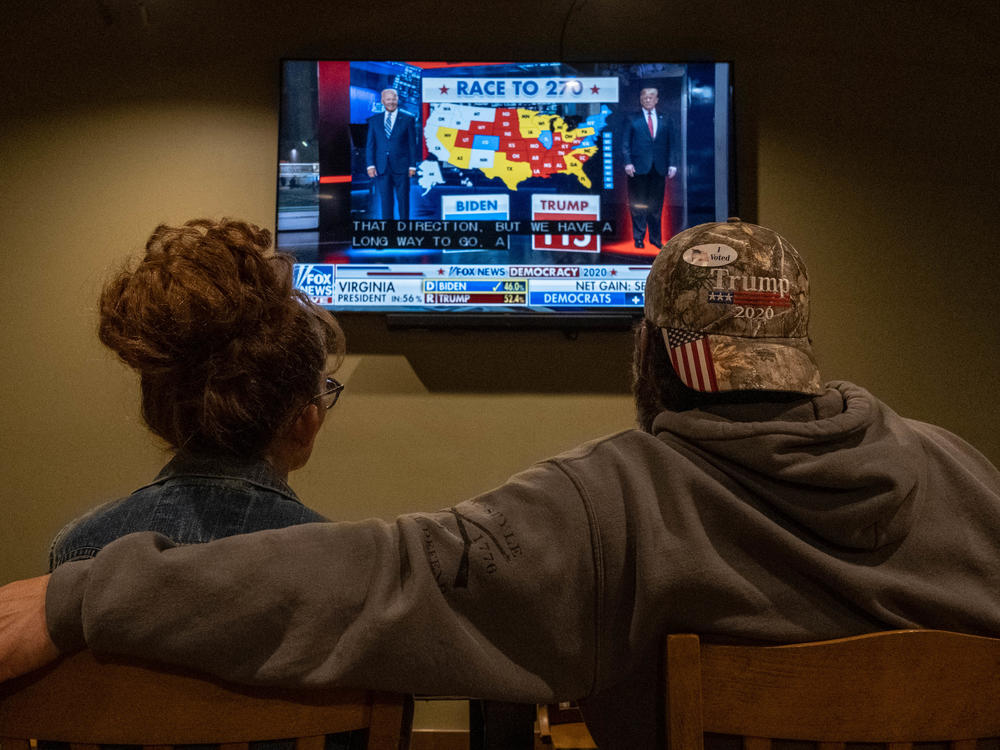 A couple watches the election results at a Republican watch party at Huron Valley Guns in New Hudson, Mich. People watching the results come in saw President Trump outperforming his position in preelection polls.